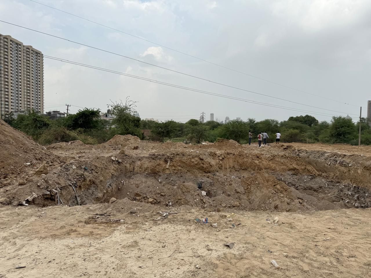 The excavated pond bed with people standing on the far bank