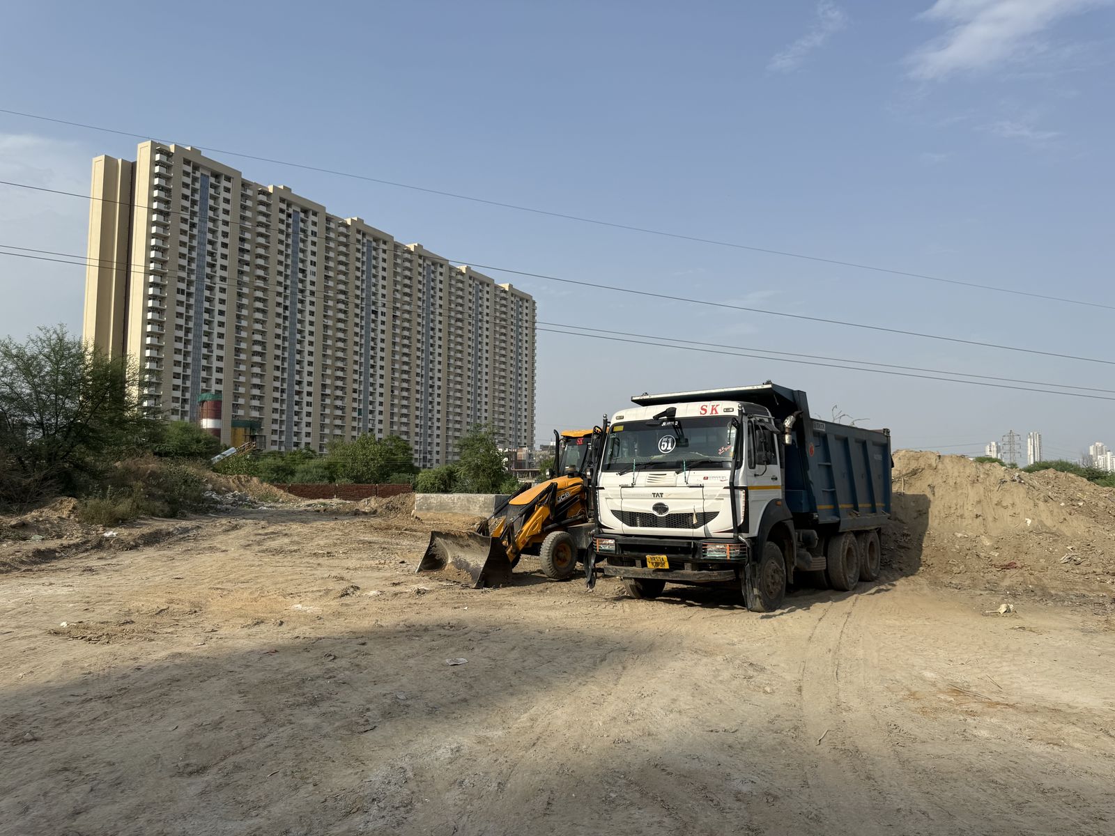 A tipper truck and backhoe loader on the cleared ground